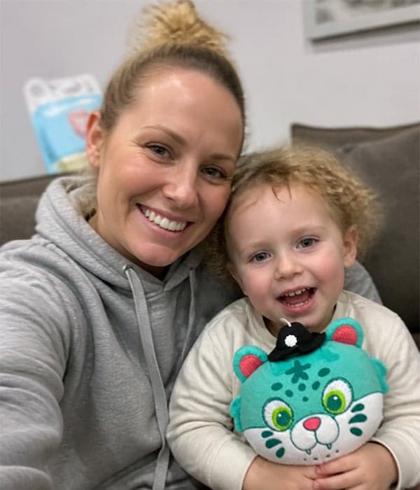 Mother and toddler smiling together with a custom teal cat-face plush pillow toy made by StarDream Toys